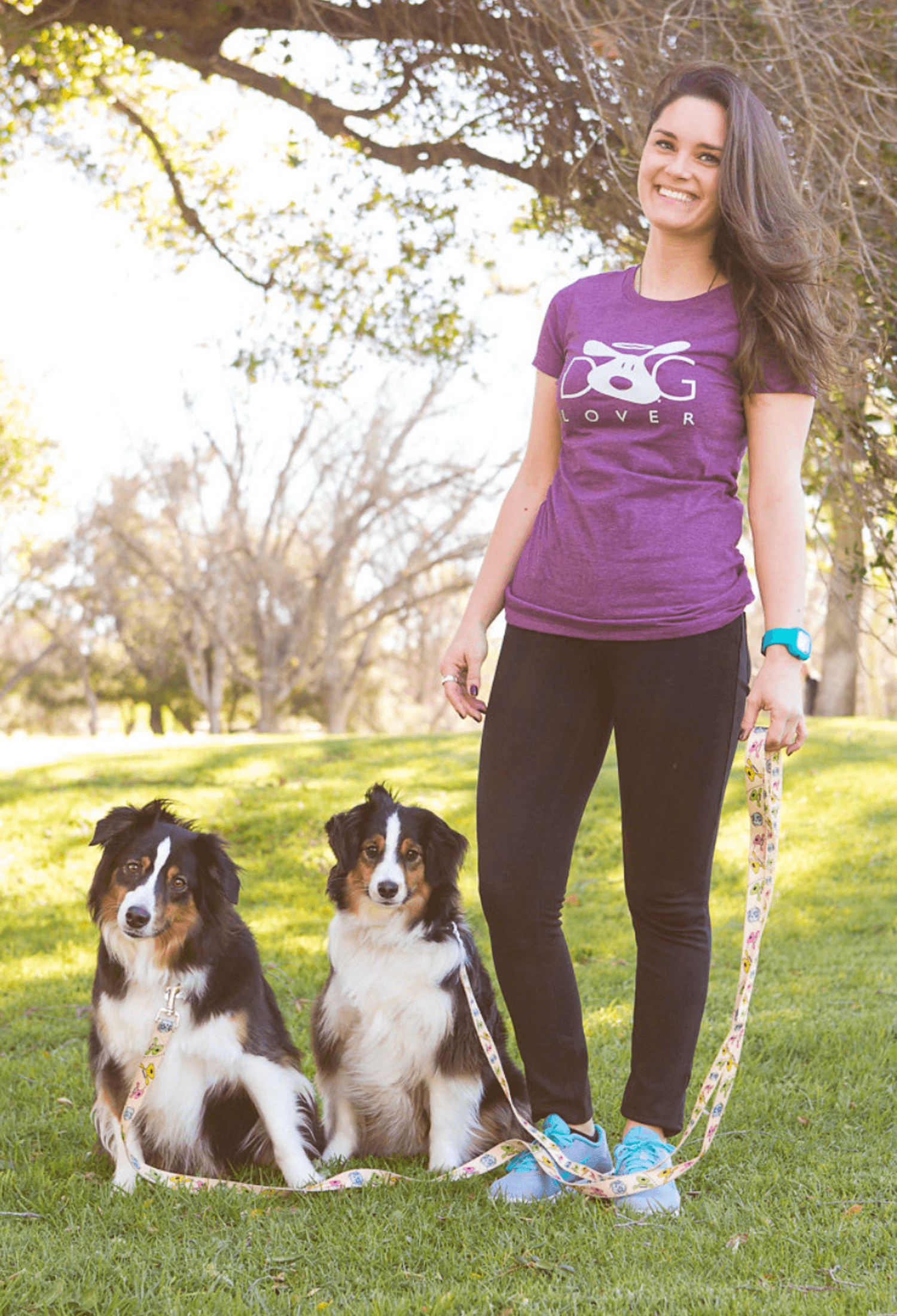 Woman wearing Dog Lover Plum-Short-Sleeved t-shirt walking two dogs in a park.